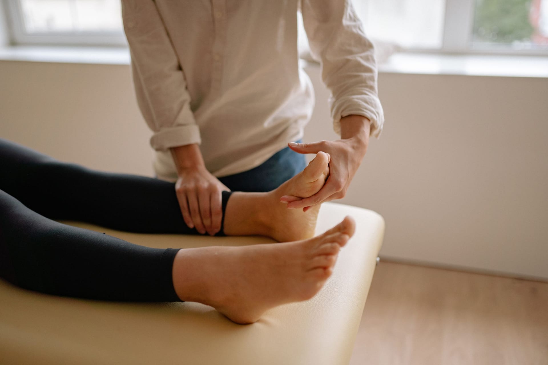 A practitioner's hands flexing a patient's forefoot at the end of a treatment table